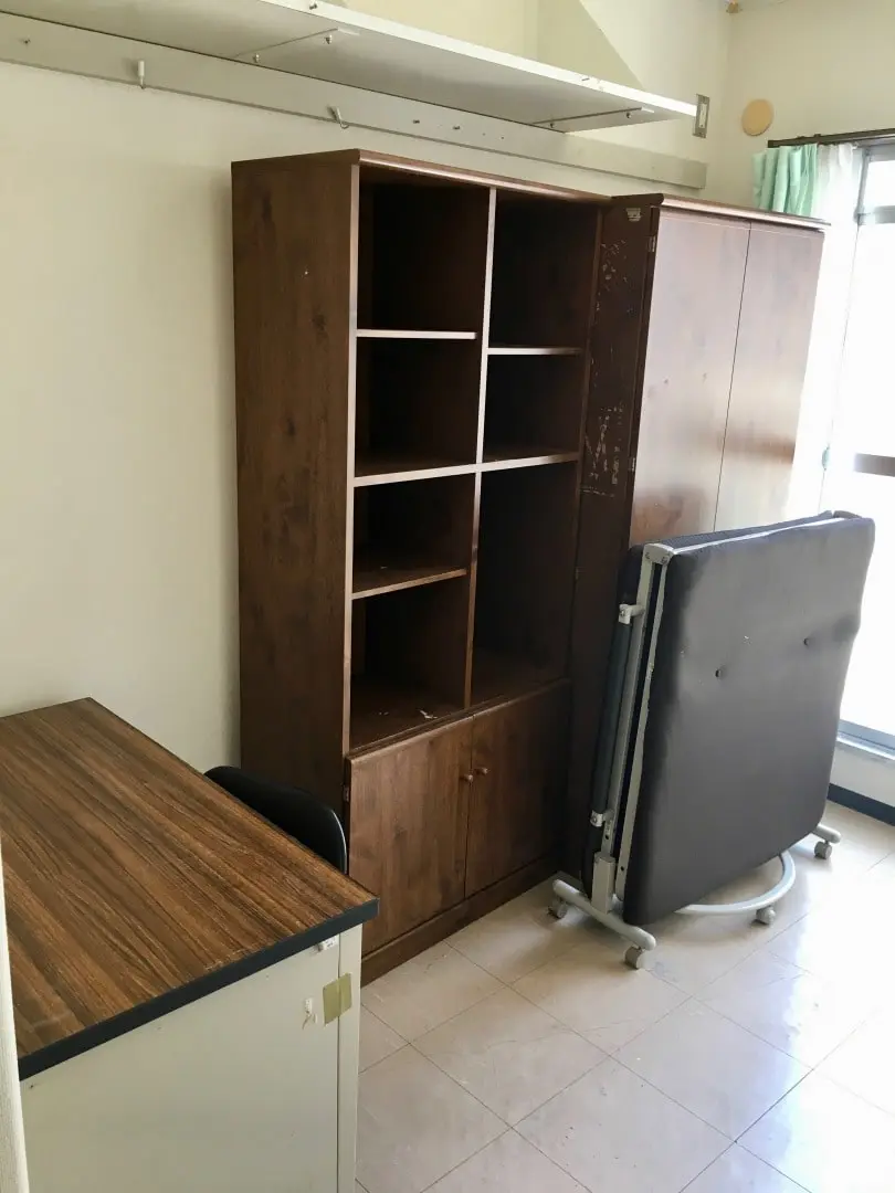 机、本棚、クローゼット、ベッドが並んでいる。部屋の1/3を埋めている